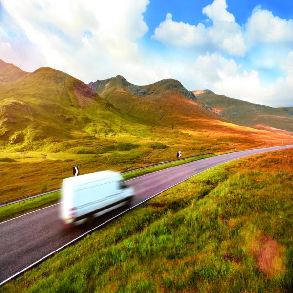 EV shipping truck on road surrounded by hills